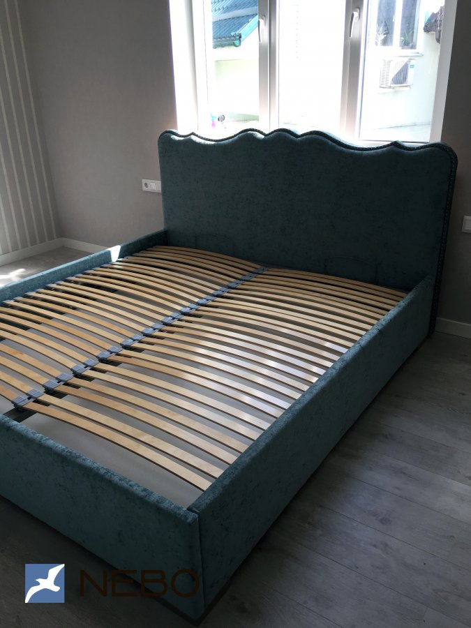 Мягкая кровать пастельно-бирюзового цвета с оригинальным криволинейным изголовьем