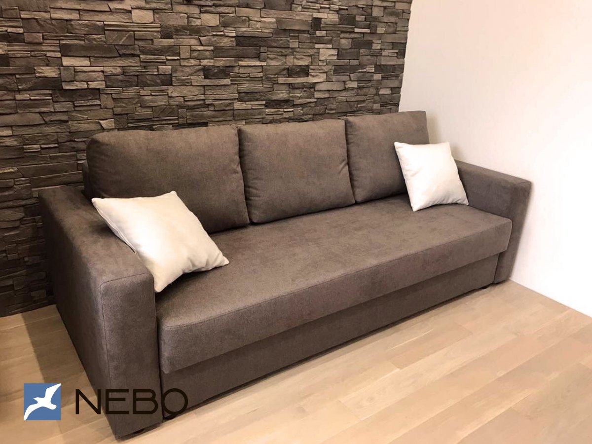 Трехместный коричневый диван-кровать с двумя белыми подушками