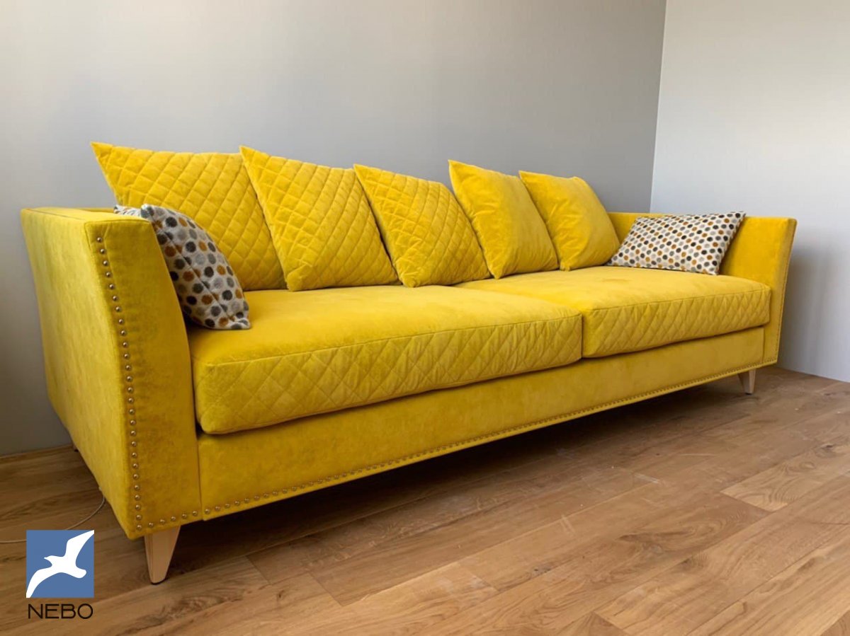 Яркий диван на деревянных ножках с декоративными подушками в обивке канареечного цвета