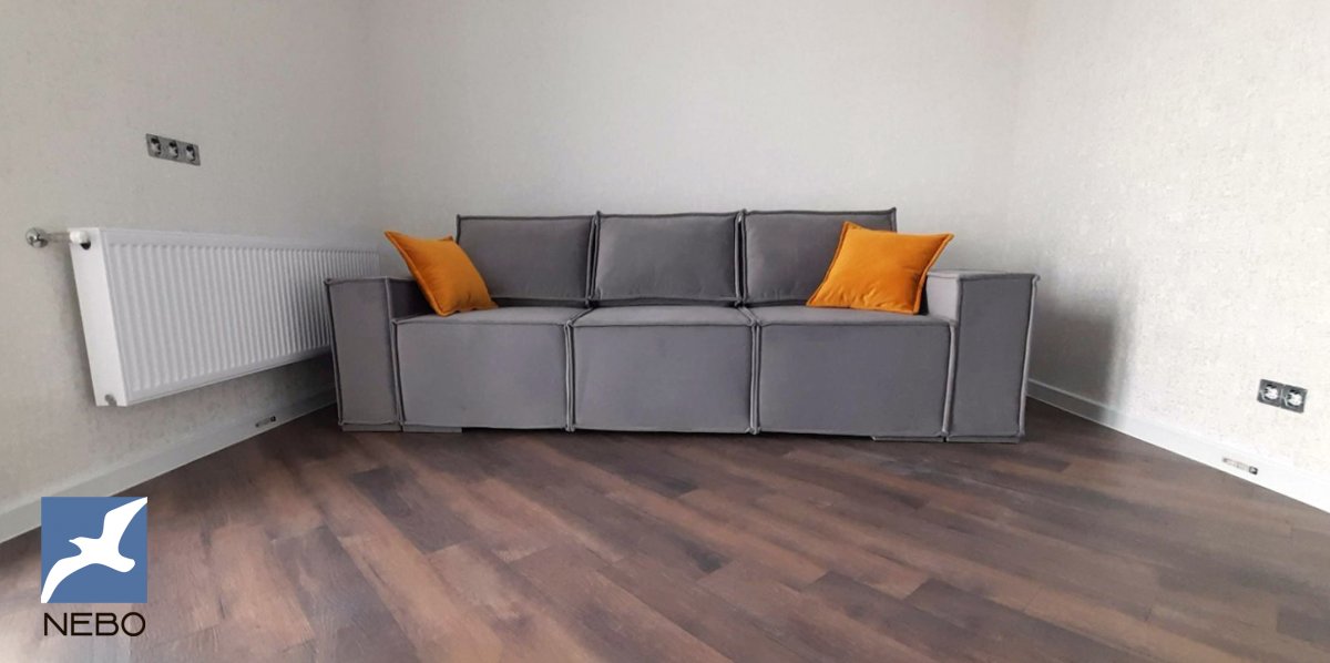 Трехместный серый диван для гостиной с кантом и оранжевыми акцентными подушками 