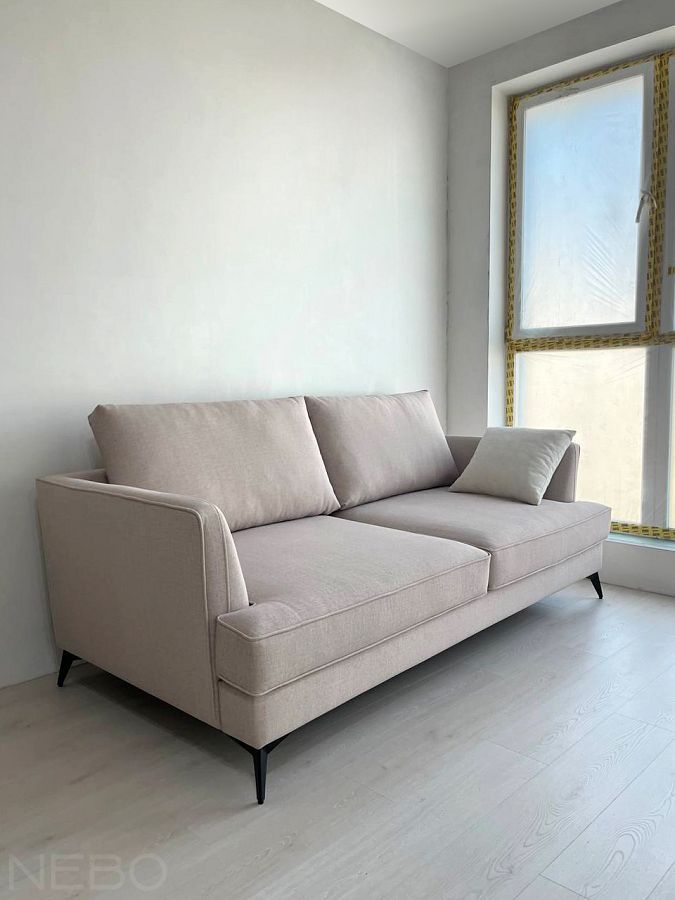 Глубокий диван в гостиную с тканью в светло-бежевом цвете и на черных тонких ножках