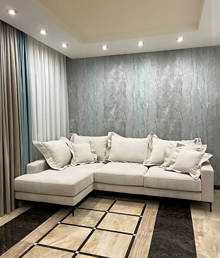 Светлый угловой диван на черных металлических ножках в гостиную