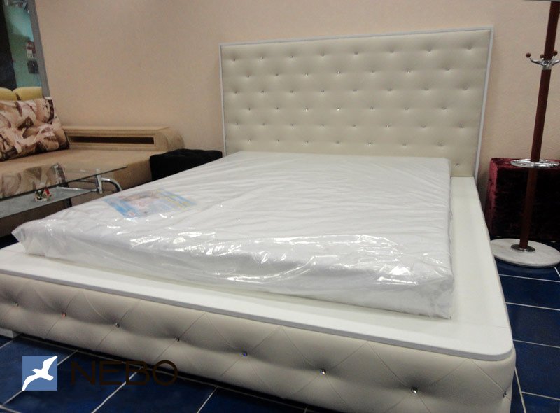 Белая мягкая двуспальная кровать с широкими бортами и пиковкой со стразами