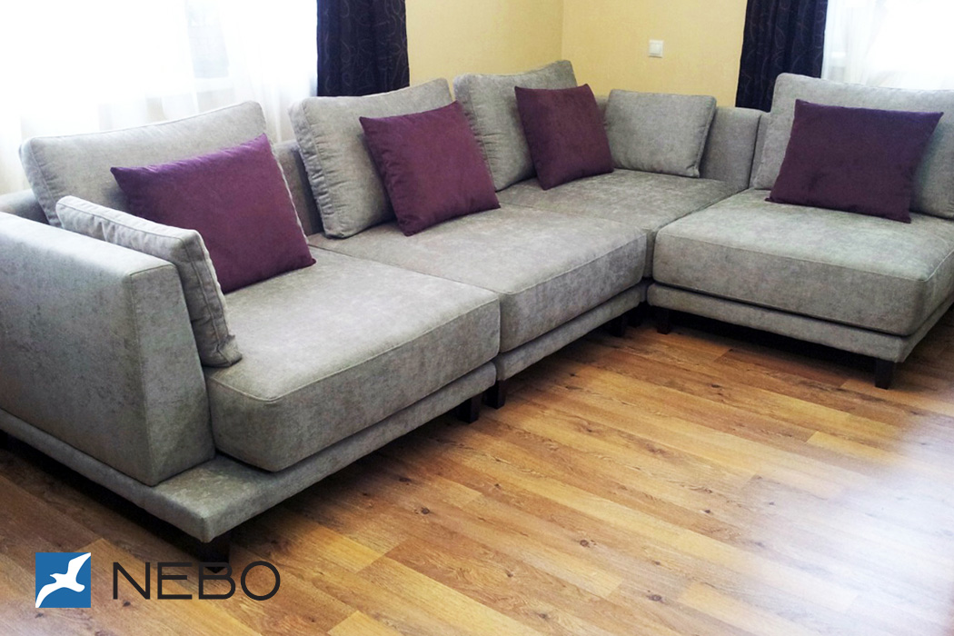 Угловой серый диван для гостиной с темно-фиолетовыми подушками и системой раскладки