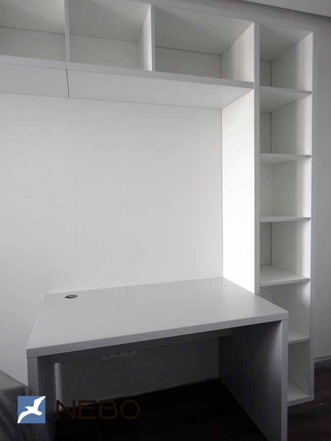 Небольшой белый компьютерный стол со встроенной системой открытых полок справа и сверху от стола