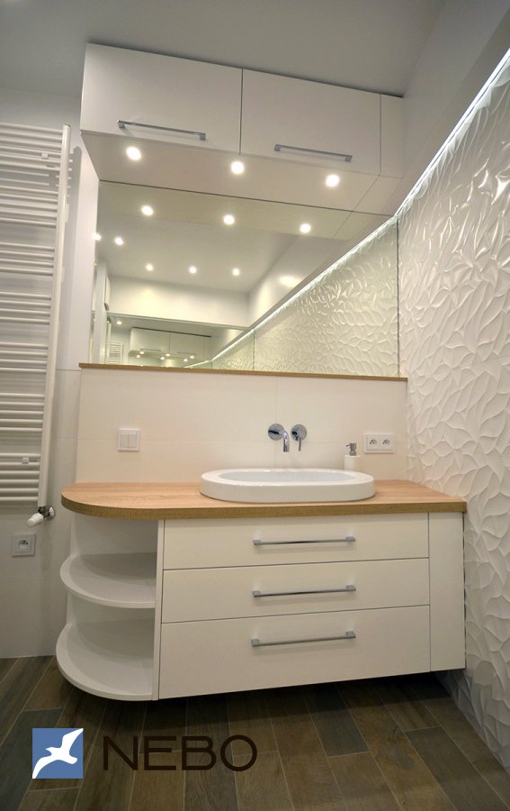 Подвесная тумба в ванную со скругленной боковой частью с открытыми полками и встроенные антресольные шкафы над зеркалом