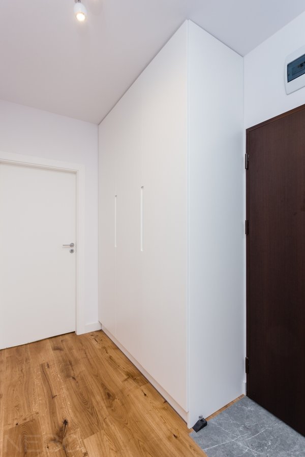 Распашной шкаф из белого крашенного МДФ с интегрированными ручками в прихожую комнату возле входной двери