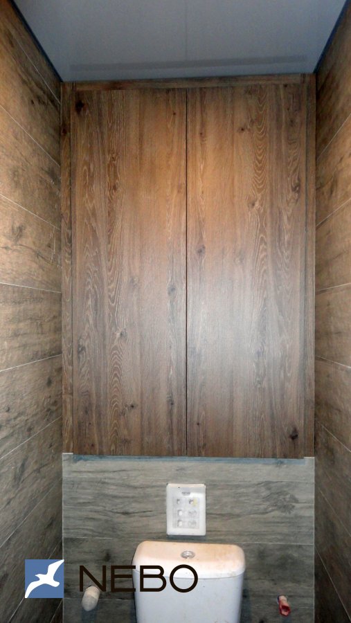 Встроенные дверцы в туалете над унитазом из ЛДСП в отделке под древесину дуба