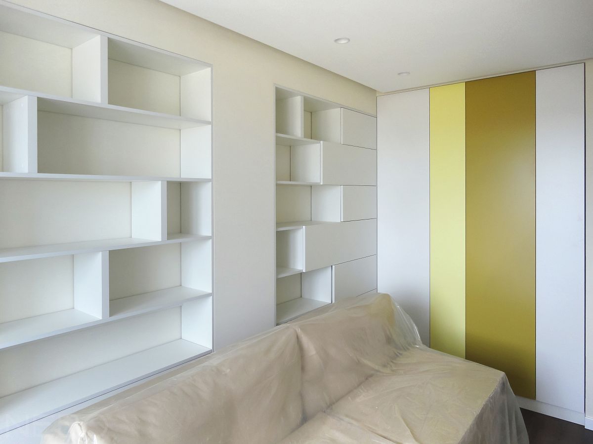 Детская мебель со встроенными шкафами и стеллажами на стене за диваном