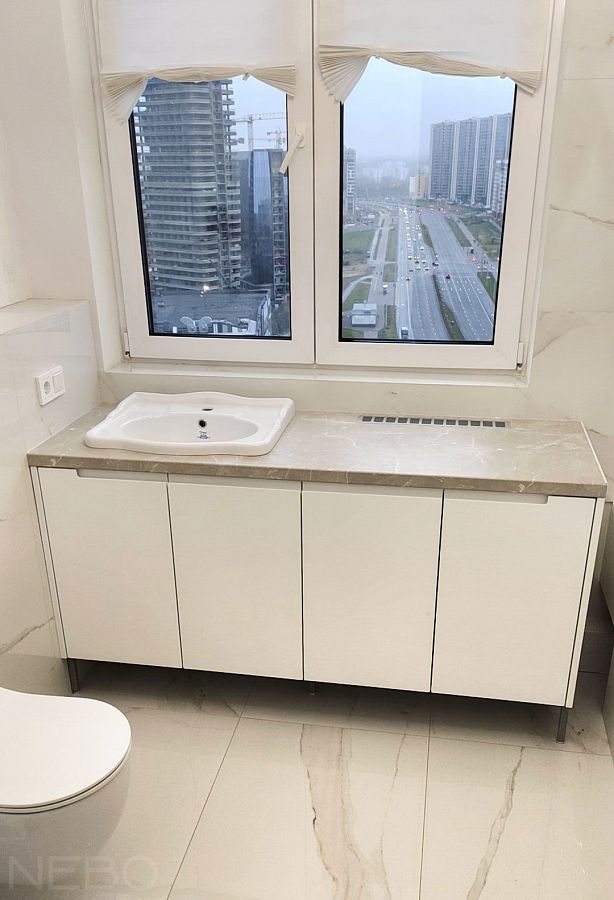 Тумба у окна вокруг радиатора отопления для ванной в квартире 