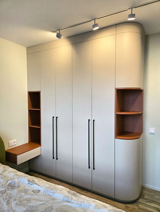 Шкаф с закруглением одной из сторон с открытыми полками и прикроватной тумбой в спальню