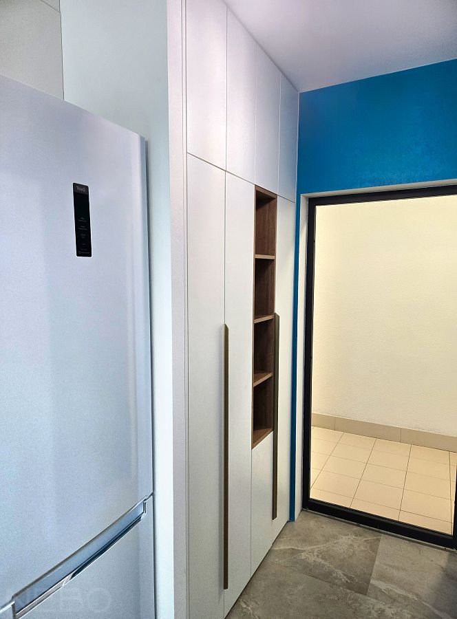 Белый шкаф встроенный в нишу в коридоре прихожей возле холодильника