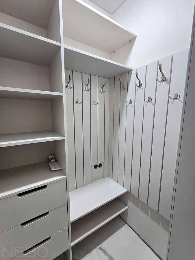 Гардеробная в прихожей комнате с вешалками, полками и выдвижными ящиками
