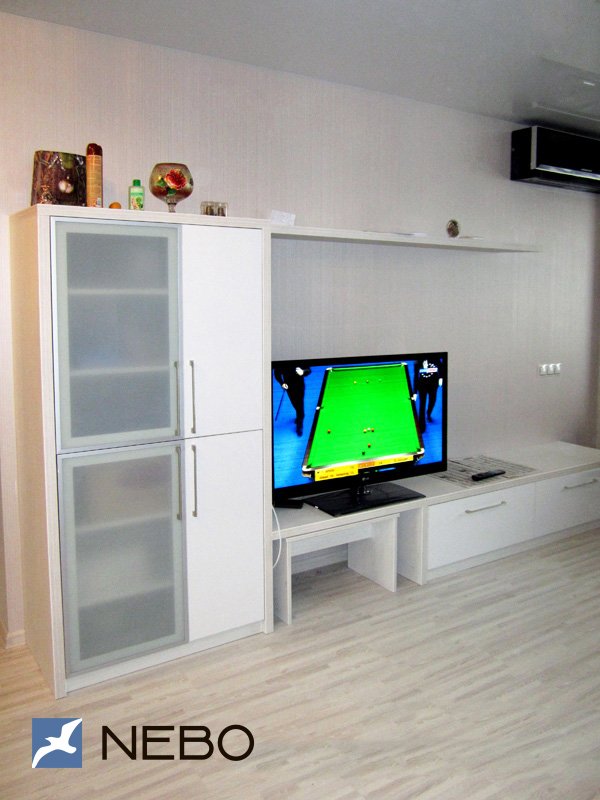 Белая мебель из ЛДСП для гостиной с распашными шкафчиками, тумбой под ТВ и открытой длинной полкой 