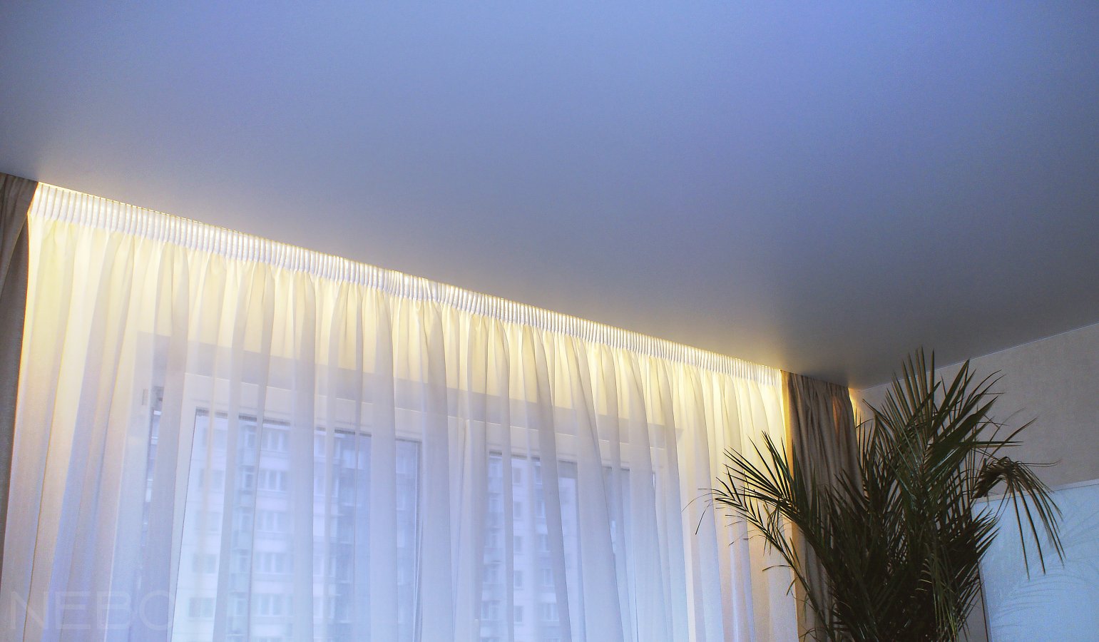 Белый матовый натяжной потолок с подсветкой штор в нише карниза в спальне