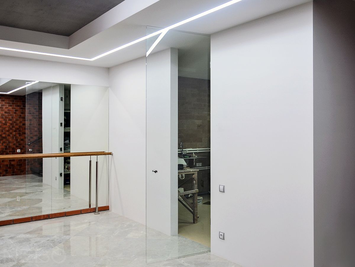 Стеклянная дверь до потолка между тренажерным залом и хозяйственным помещением в частном доме