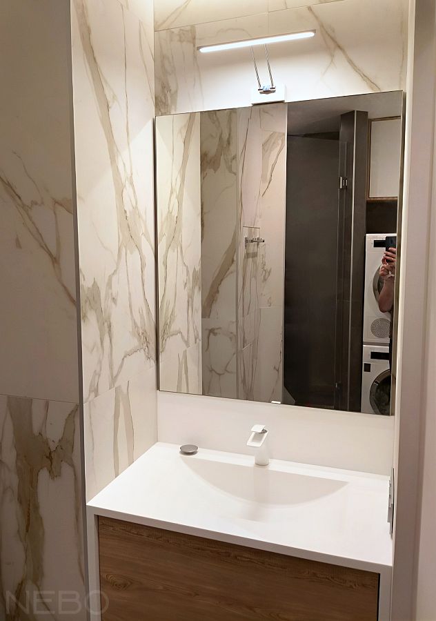 Прямоугольное зеркало в тонкой алюминиевой рамке над раковиной в ванной