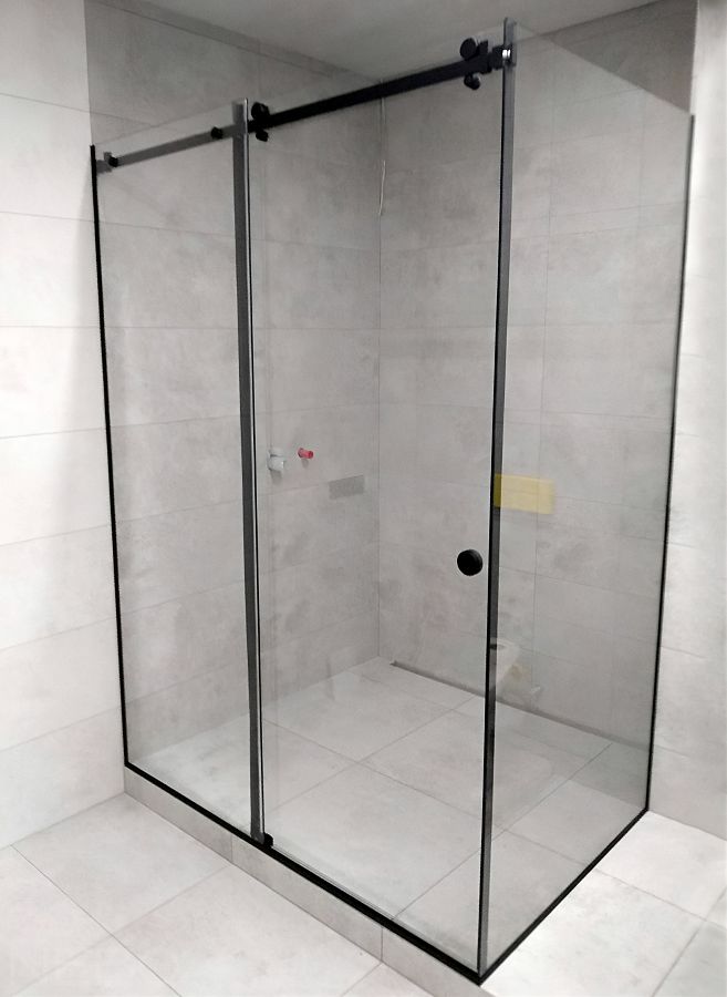 Угловая душевая кабина из осветленного закаленного стекла с черной фурнитурой и установкой на подиум из плитки