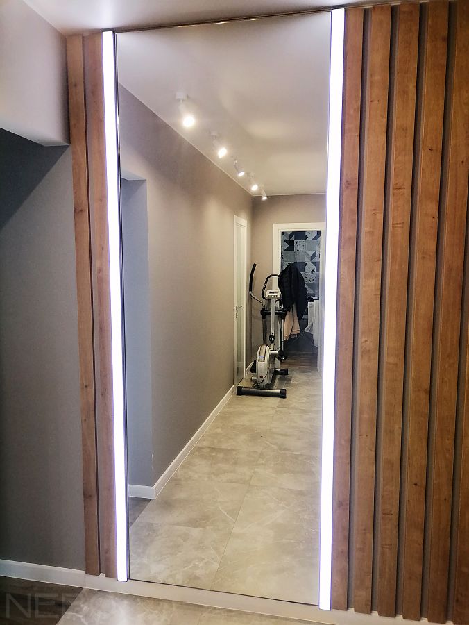 Зеркало от пола до потолка между световыми профилями и декоративными рейками