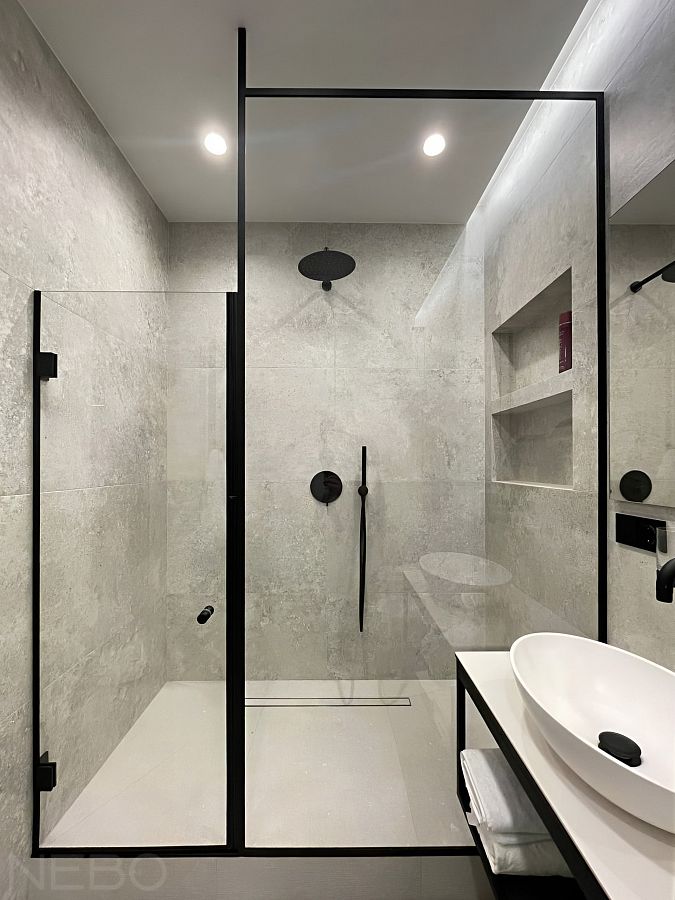 Стеклянное ограждение душевой с дверью и перегородкой разной высоты в черном профиле