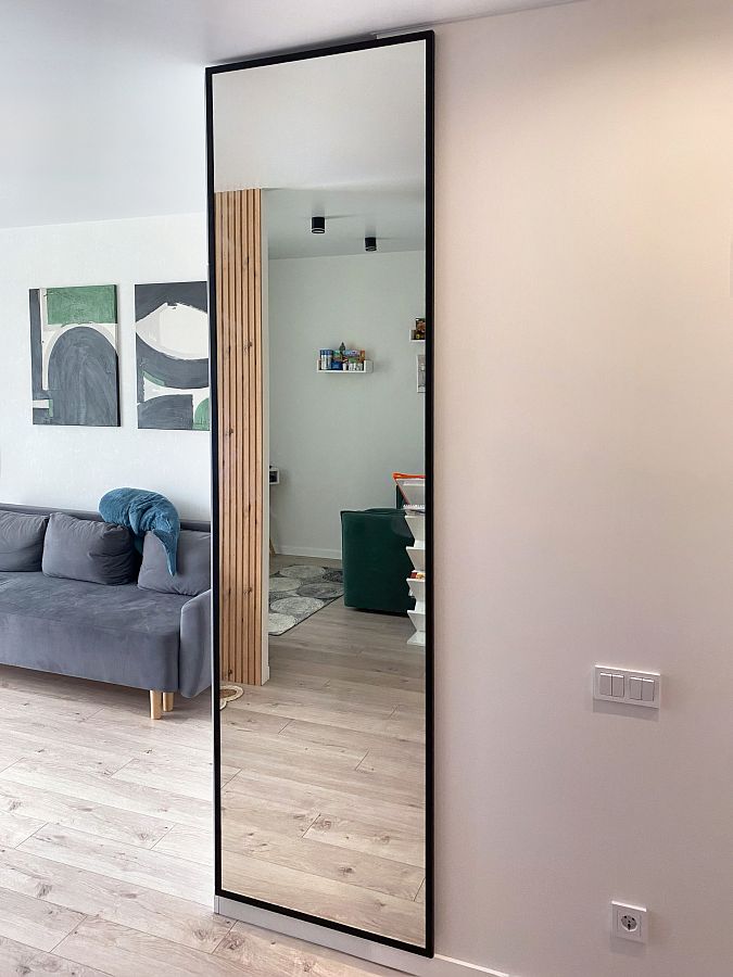 Высокое зеркало от пола до потолка в черной рамке для прихожей в квартире-студии