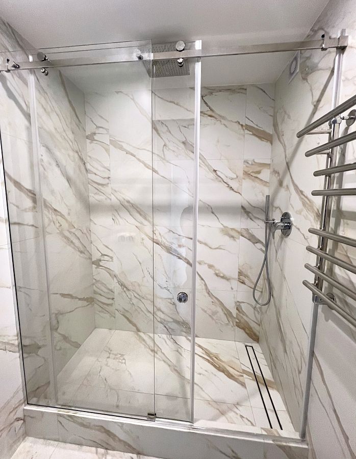 Стеклянная раздвижная перегородка для душа с установкой на подиум из плитки