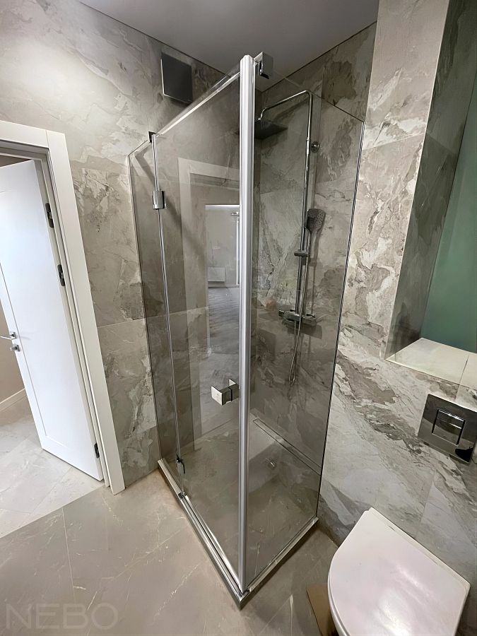 Угловая душевая перегородка с дверью из прозрачного стекла и глянцевой фурнитурой хром