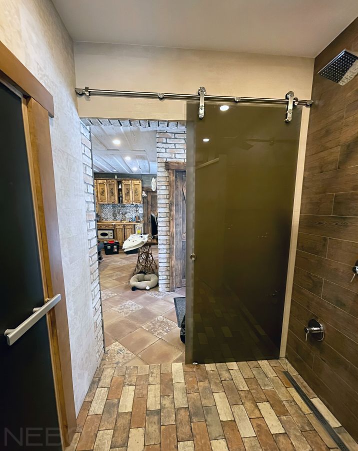 Дверь из матового бронзового стекла с амбарным механизмом в сауну в частном доме