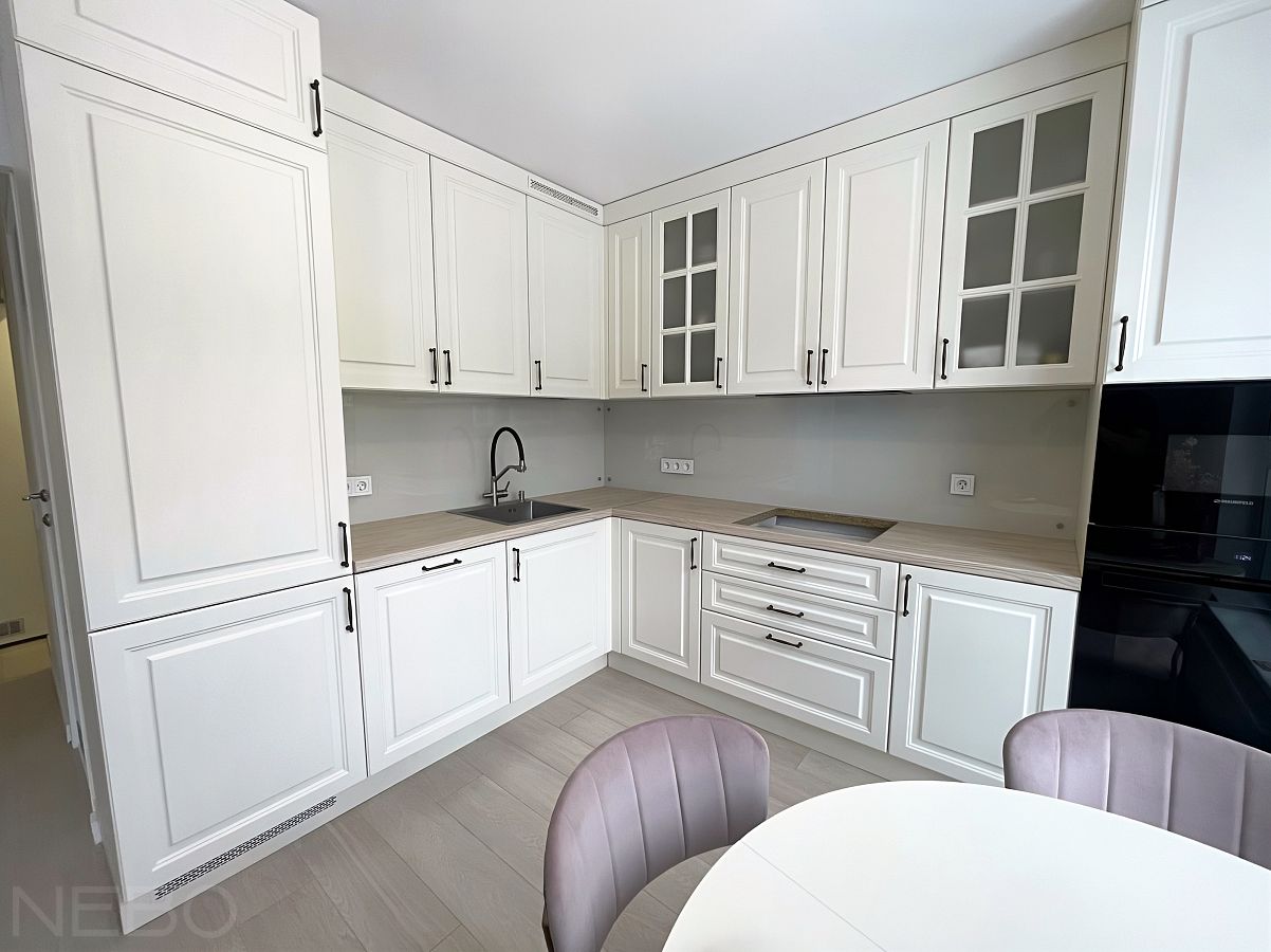 Светло-бежевый стеклянный фартук для белой угловой кухни в классическом стиле