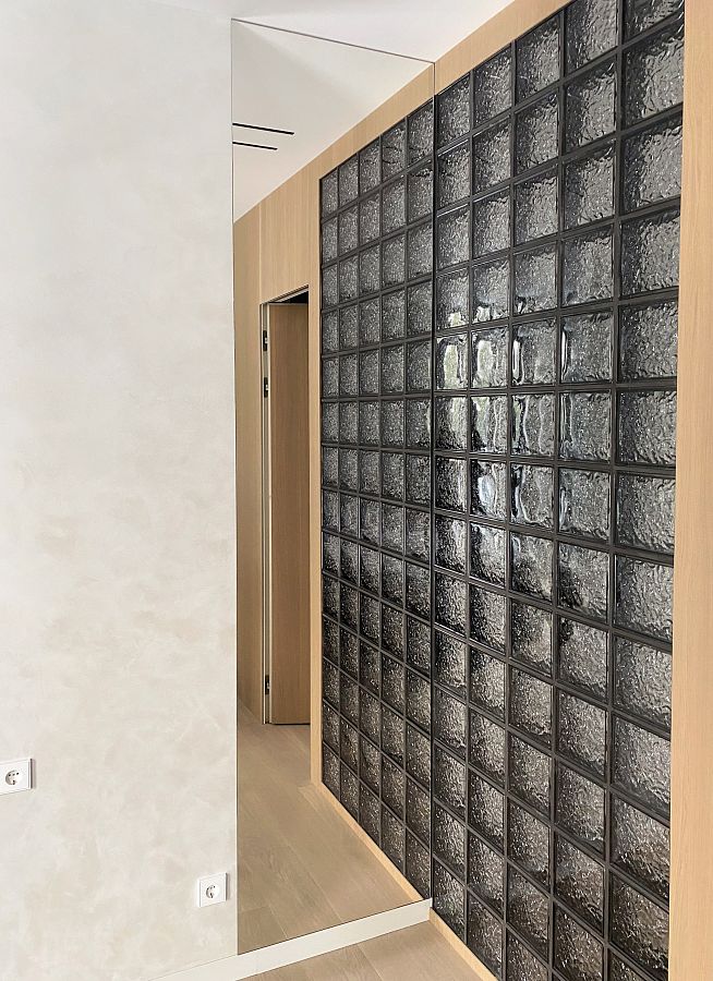 Высокое зеркало от скрытого встроенного плинтуса и до потолка возле стены из стеклоблоков в спальне